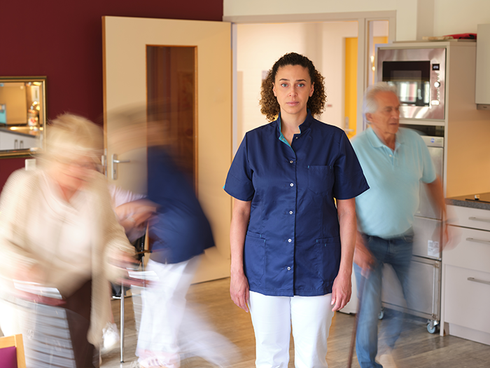 een verpleger in een instelling met bewegende mensen om haar heen